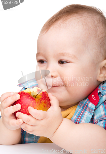 Image of Little child is eating red apple and smile