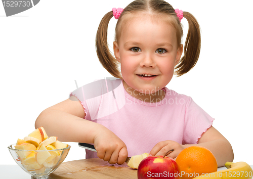 Image of Little girl is cutting fruits for salad