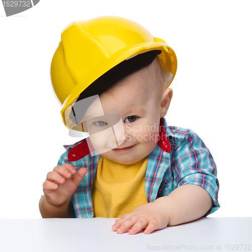 Image of Cute little boy wearing oversized hard hat