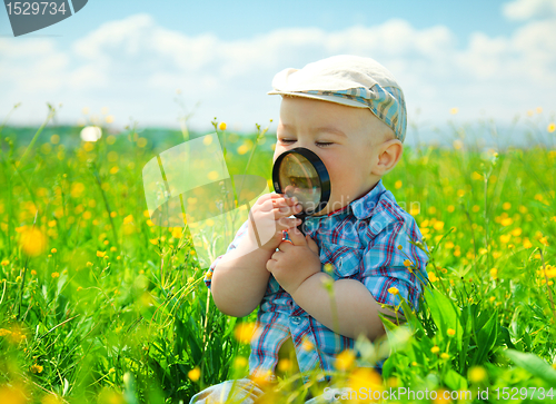 Image of Little boy is playing with magnifier