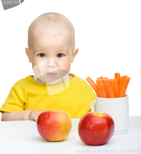 Image of Cute little boy eats carrot and apples