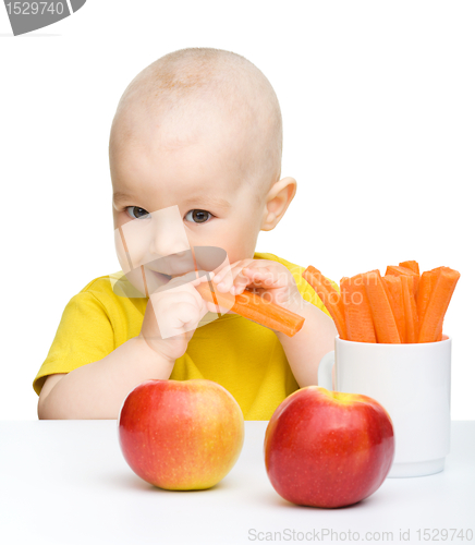 Image of Cute little boy eats carrot and apples