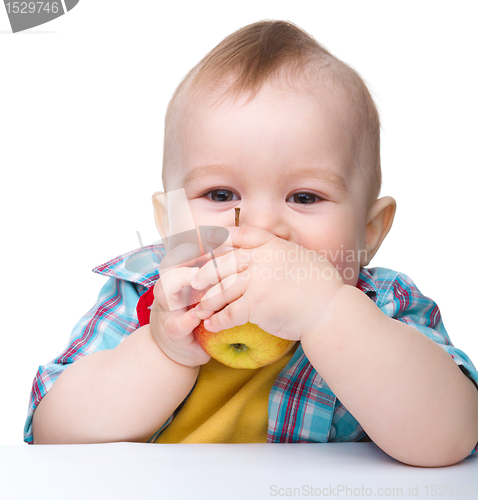 Image of Little child is biting red apple and smile