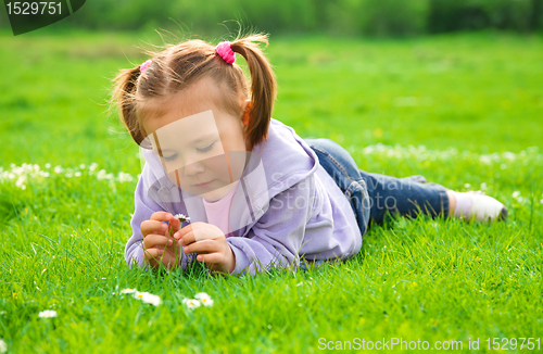 Image of Little girl is laying on green meadow