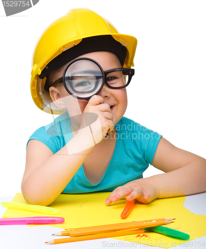 Image of Cute little girl is looking through magnifier