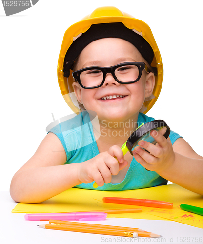 Image of Cute little girl is playing while wearing hard hat