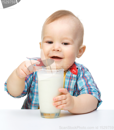 Image of Cute little boy is holding big glass of milk