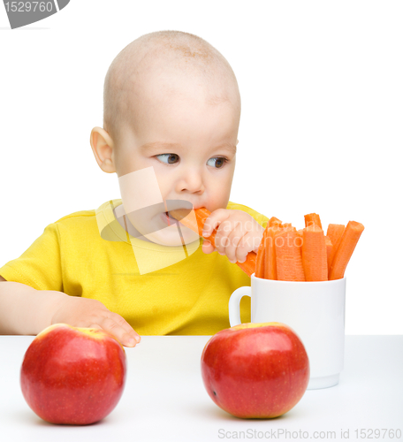 Image of Cute little boy eats carrot and apples