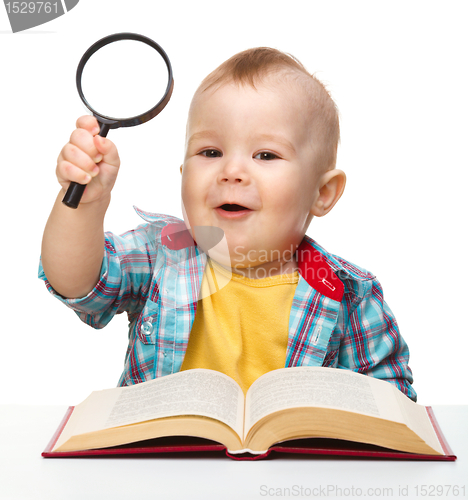 Image of Little child play with book and magnifier