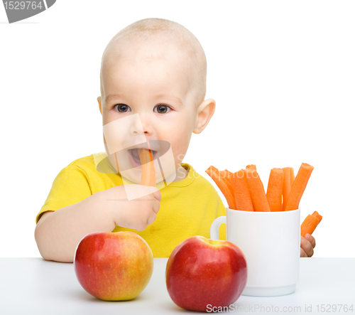 Image of Cute little boy eats carrot and apples