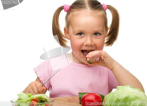 Image of Little girl is cutting carrot for salad