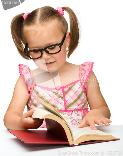 Image of Little girl is flipping over pages of a book