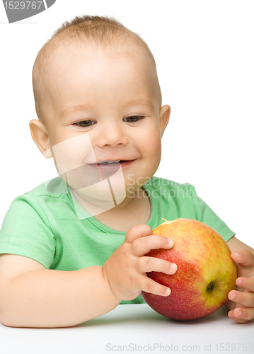 Image of Little child is biting red apple