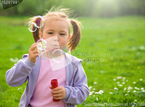 Image of Little girl blows soap bubbles on meadow