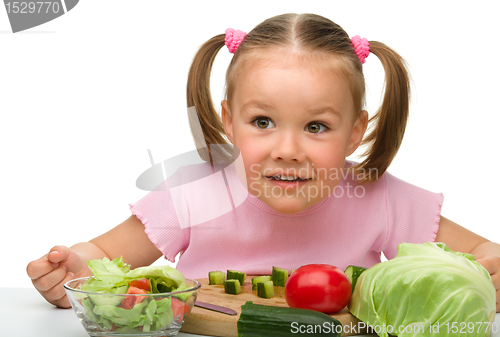Image of Little girl is cutting carrot for salad