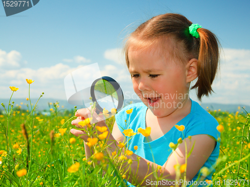 Image of Little girl examining flowers using magnifier