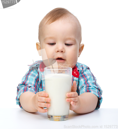 Image of Cute little boy is holding big glass of milk