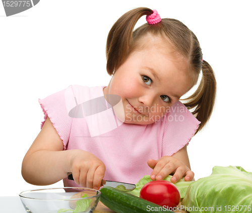 Image of Little girl is cutting carrot for salad