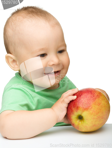 Image of Little child is biting red apple