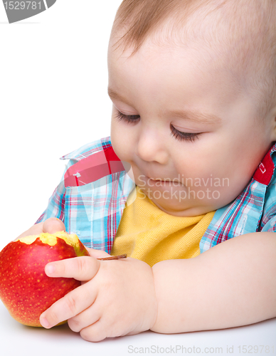 Image of Little child is eating red apple