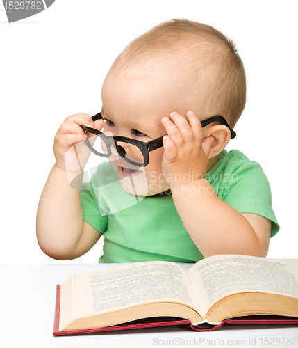 Image of Little child play with book and glasses