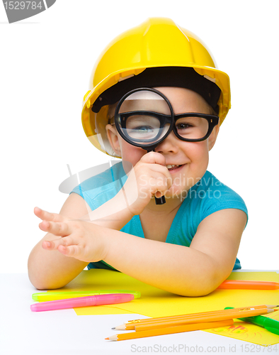 Image of Cute little girl is looking through magnifier