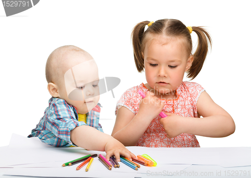 Image of Two children are drawing on paper using markers