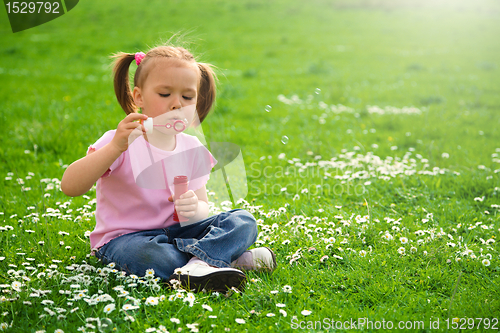 Image of Little girl is sitting on green meadow