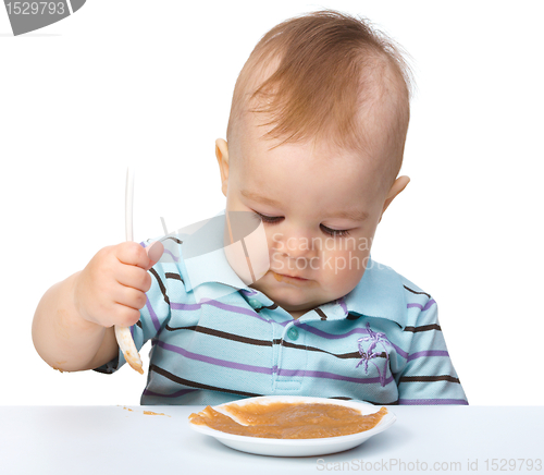 Image of Cute little boy is playing with fruit puree
