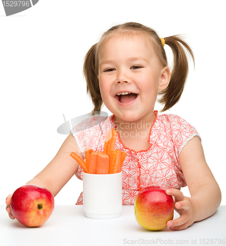 Image of Cute little girl eats carrot and apples