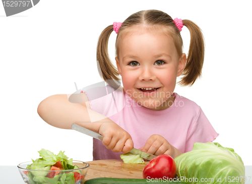 Image of Little girl is cutting carrot for salad