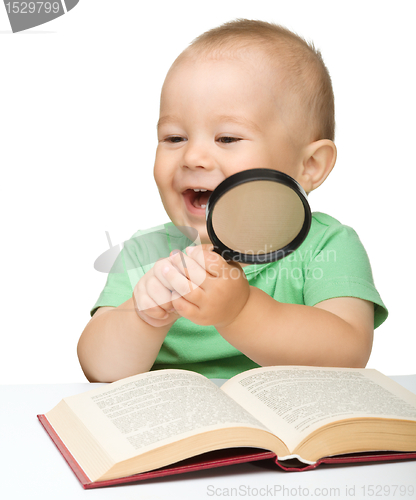 Image of Little child play with book and magnifier