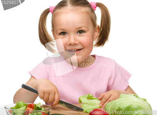 Image of Little girl is cutting carrot for salad