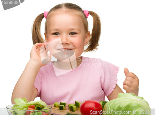 Image of Little girl is cutting carrot for salad