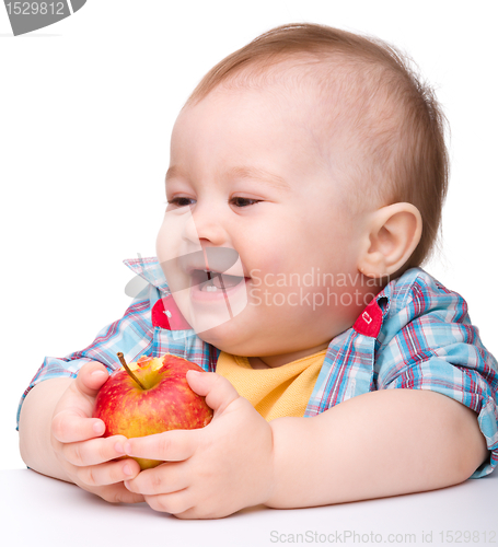 Image of Little child is eating red apple and smile