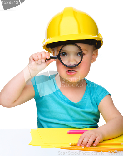 Image of Cute little girl is looking through magnifier