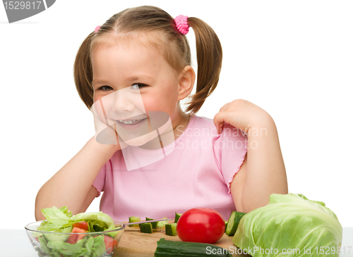 Image of Little girl is cutting carrot for salad