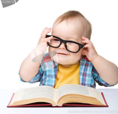 Image of Little child play with book and glasses