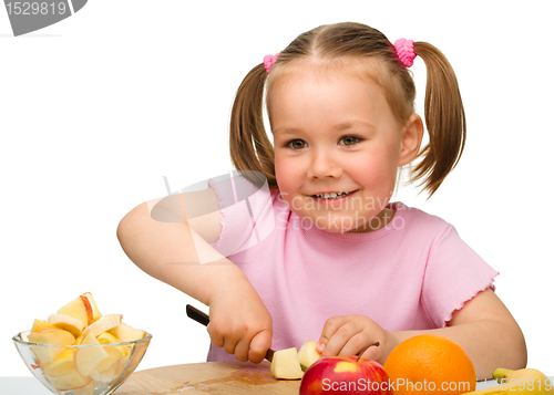 Image of Little girl is cutting fruits for salad