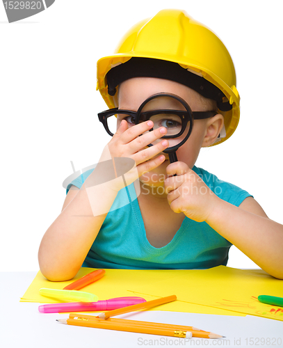 Image of Cute little girl is looking through magnifier