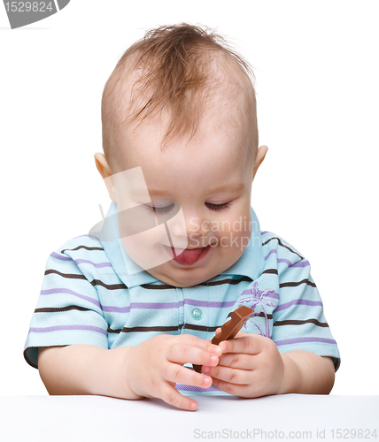 Image of Cute little boy is holding chocolate bar and smile