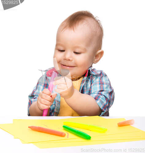 Image of Happy little boy is playing with colorful markers