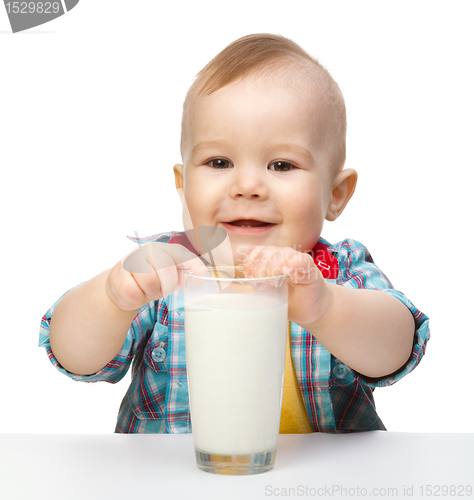Image of Cute little boy is holding big glass of milk
