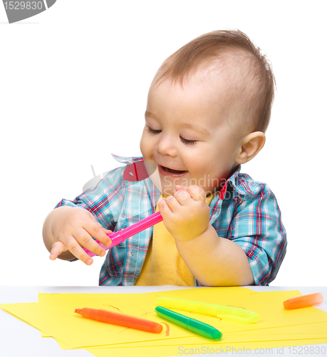 Image of Happy little boy is playing with colorful markers