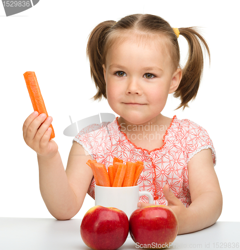 Image of Cute little girl eats carrot and apples