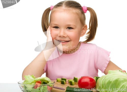 Image of Little girl is cutting carrot for salad