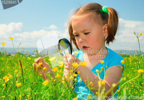Image of Little girl examining flowers using magnifier