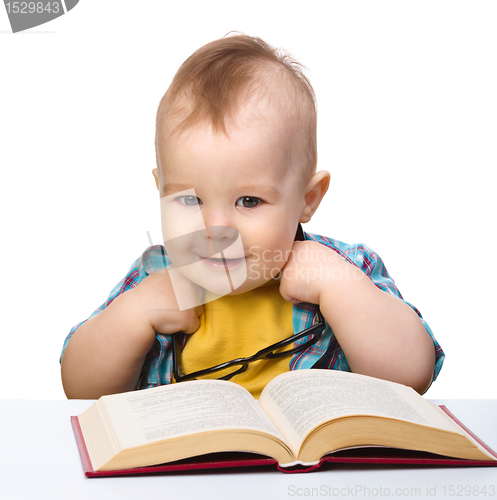 Image of Little child play with book and glasses