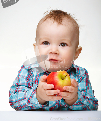 Image of Little child is eating red apple
