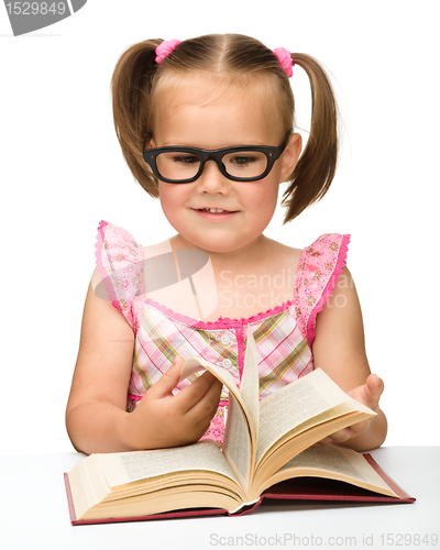 Image of Little girl is flipping over pages of a book